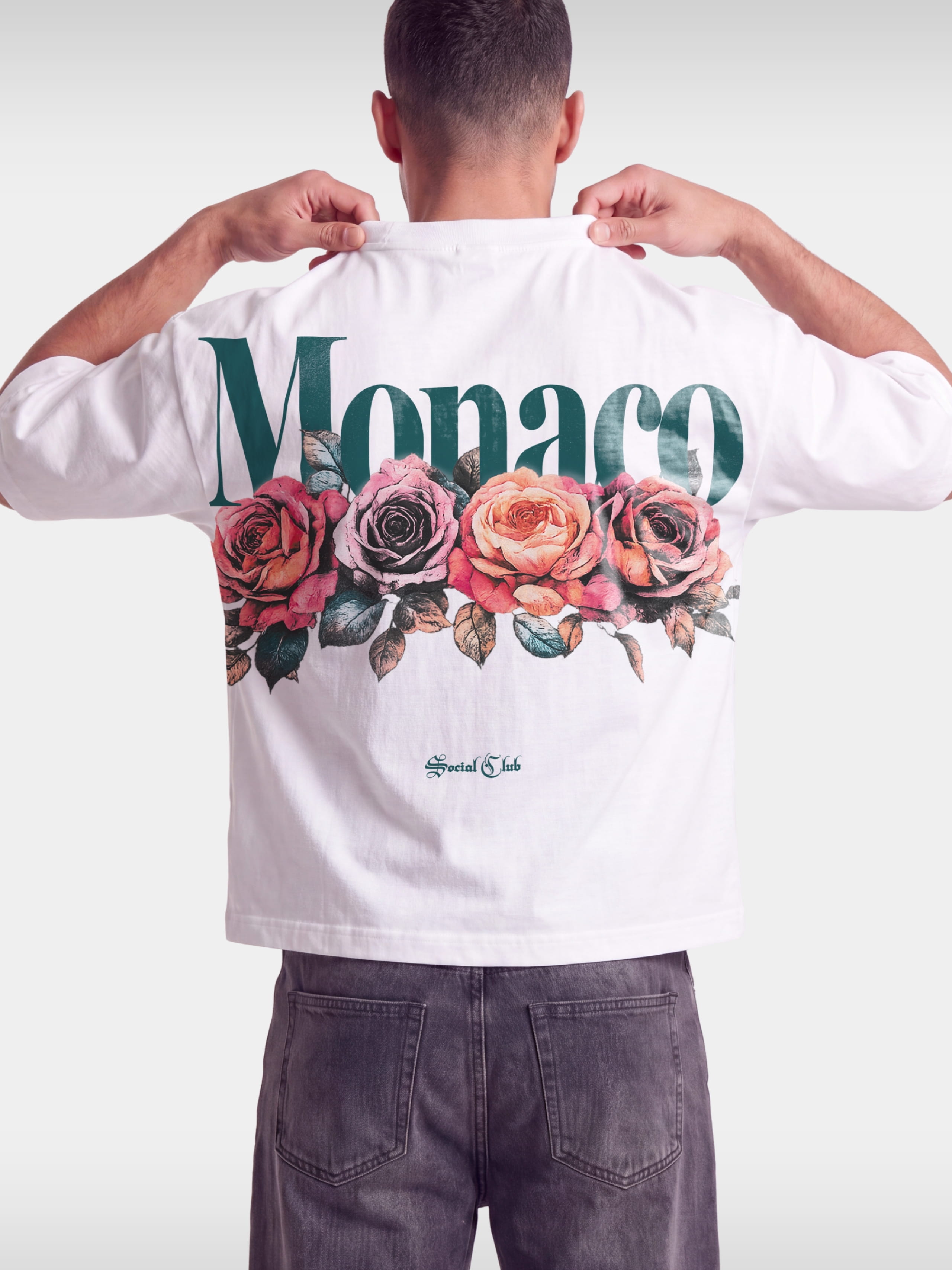 Monaco Bloom white boxy tee worn by model, back view with green Monaco wordmark and roses.