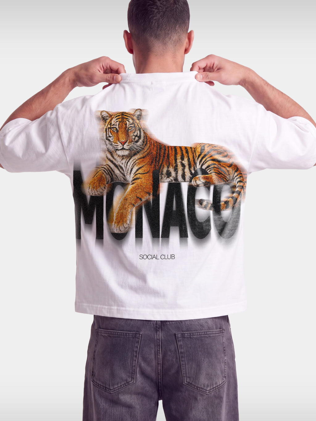 Monaco Tiger white boxy tee worn by model, back view with reclining tiger over blurred wordmark.