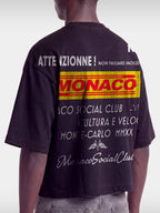 Cropped back view of Monaco Trackside black boxy tee on model, ATTENZIONNE racing text print.