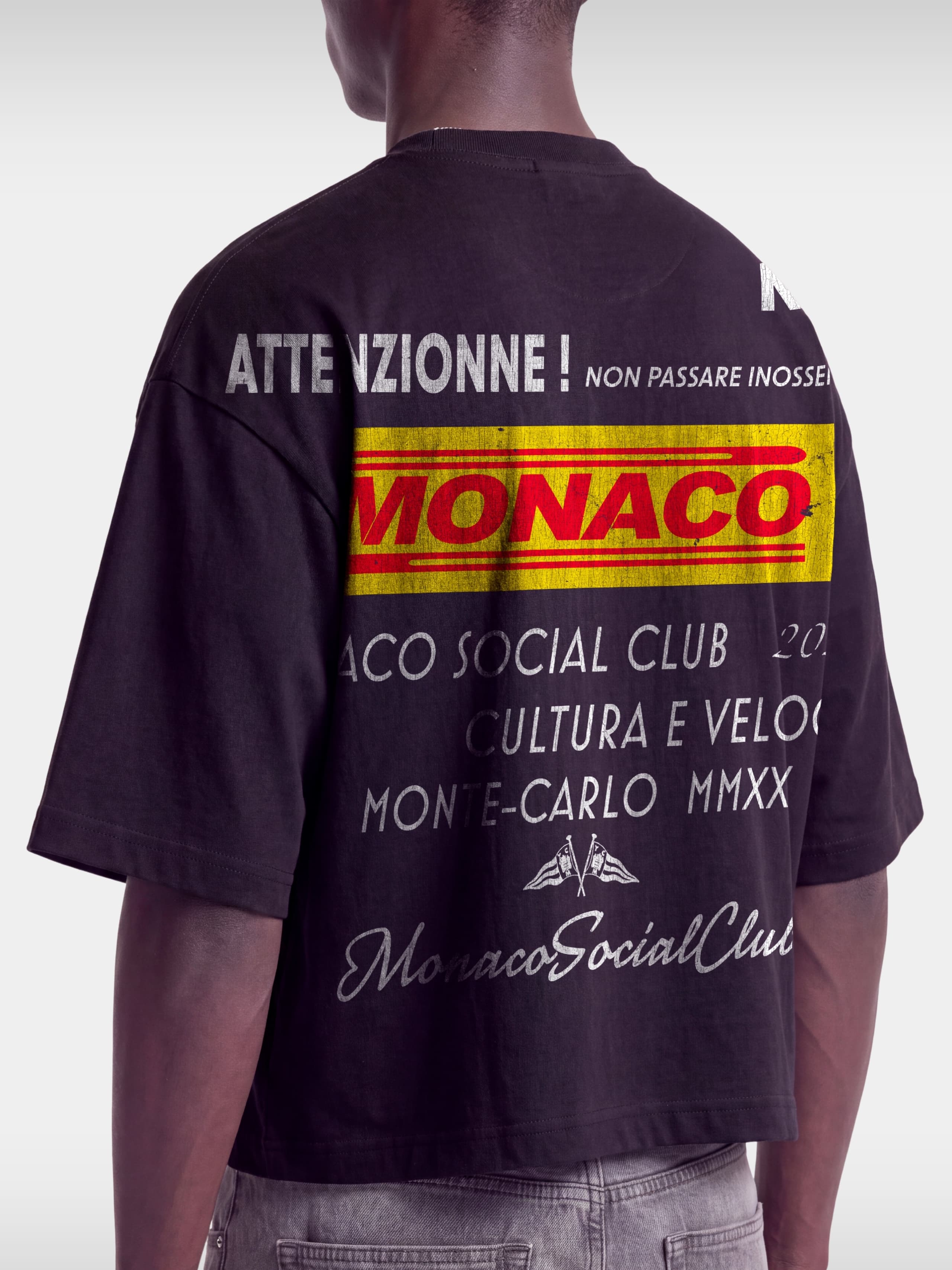 Cropped back view of Monaco Trackside black boxy tee on model, ATTENZIONNE racing text print.