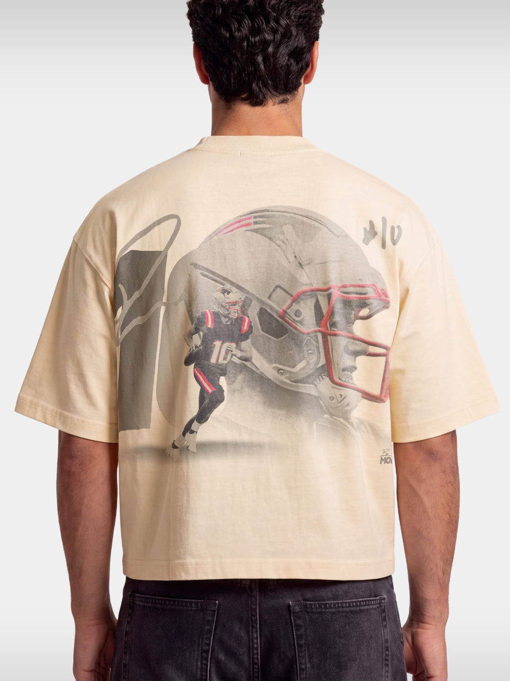 Ivory No. 10 Franchise boxy tee worn by model, back view with faded football helmet graphic.