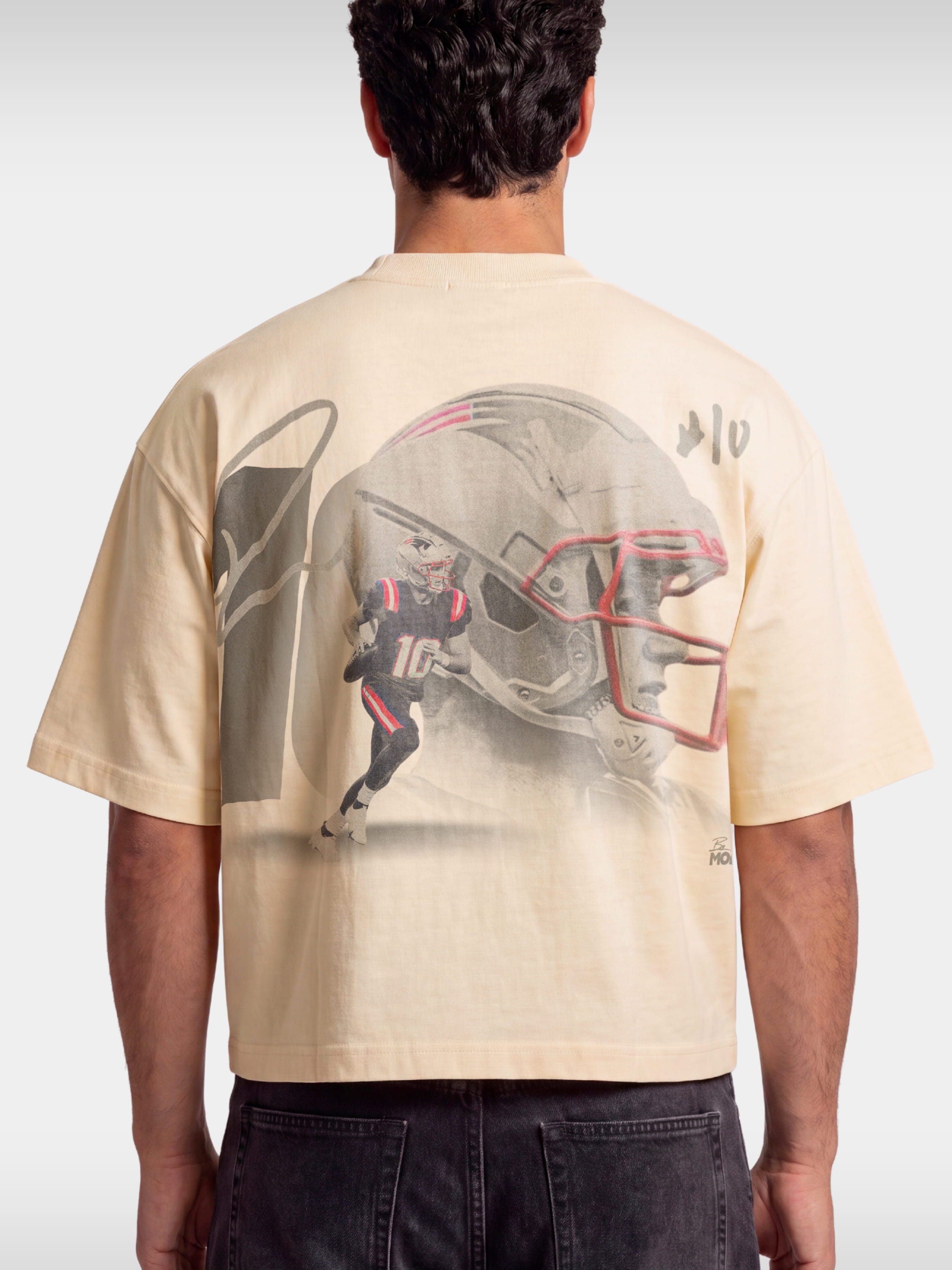Ivory No. 10 Franchise boxy tee worn by model, back view with faded football helmet graphic.