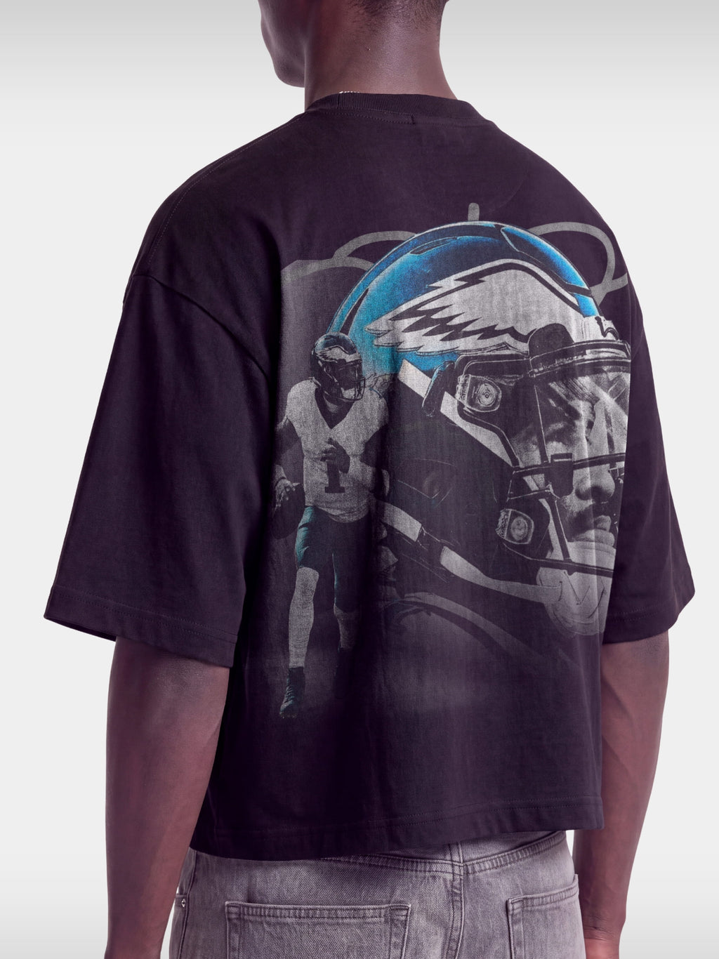Monaco No. 1 Flight boxy tee in black, worn by model, angled view with teal winged helmet and quarterback graphic.