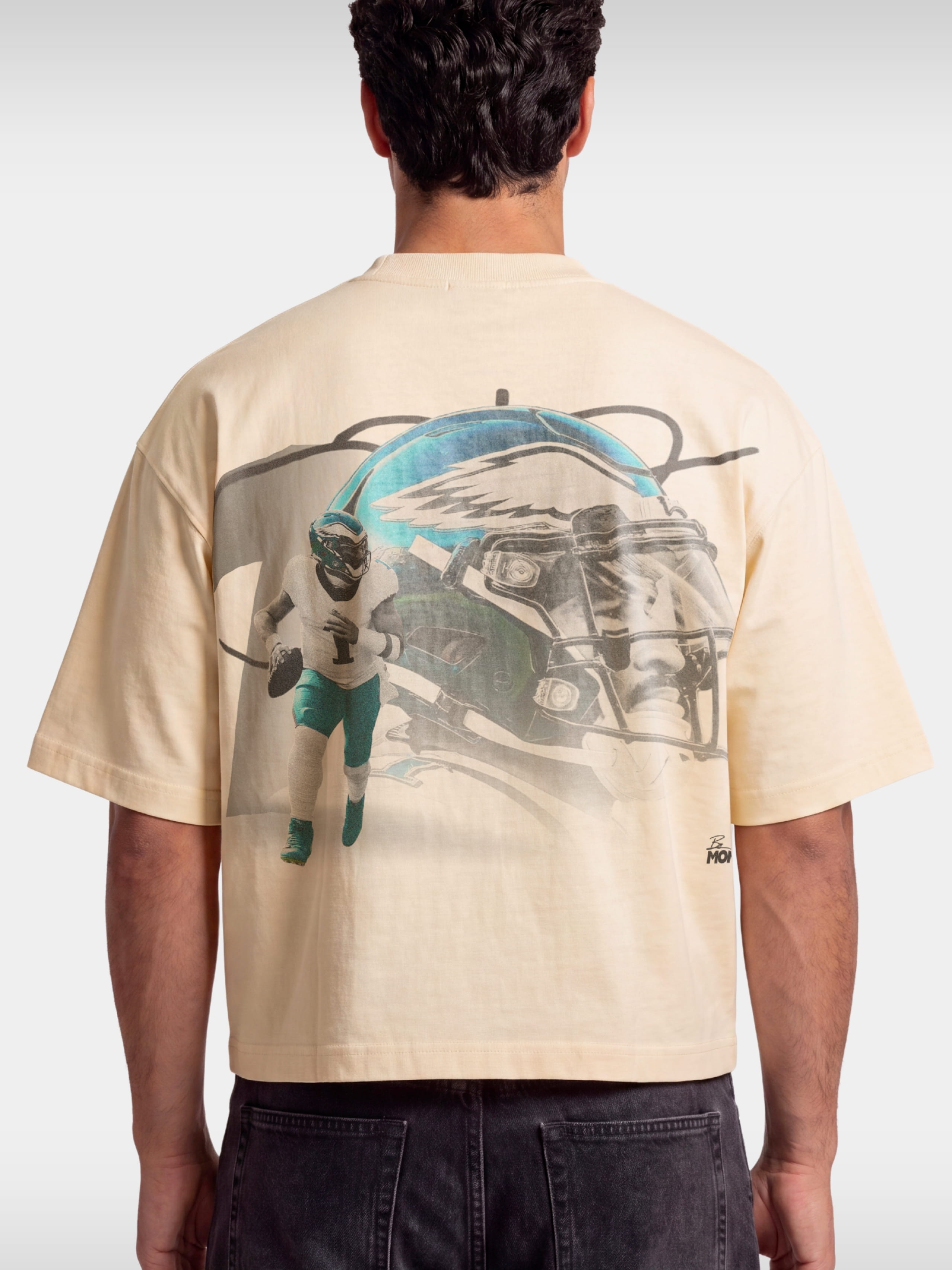Ivory No. 1 Flight boxy tee worn by model, back view with faded helmet and quarterback graphic.
