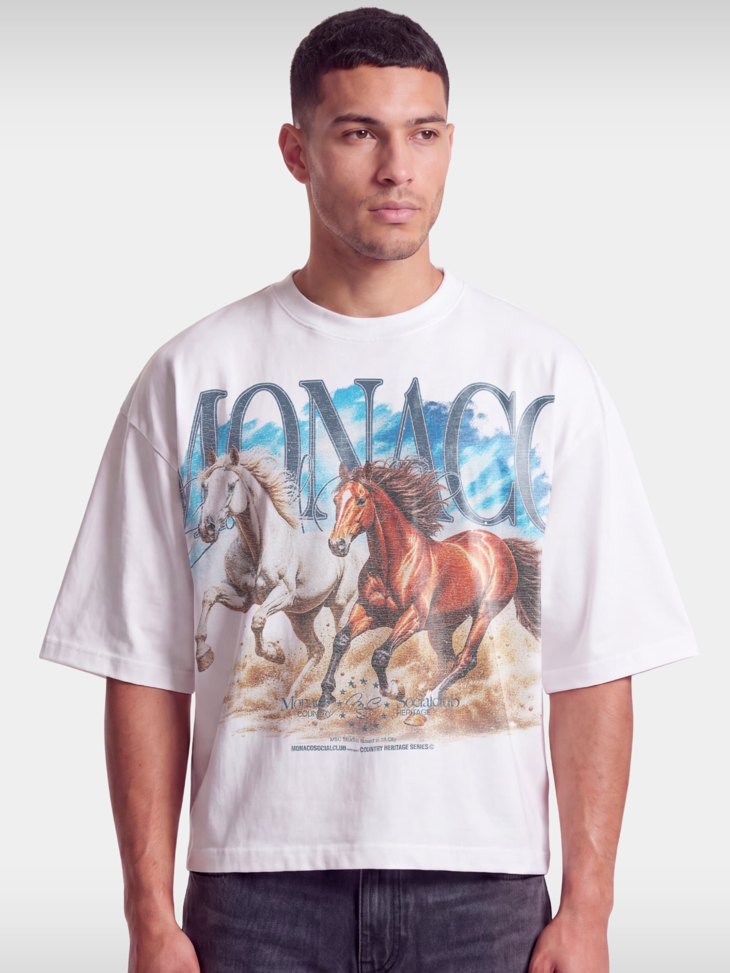 Monaco Run Wild white boxy tee worn by model, front view with galloping horses graphic.