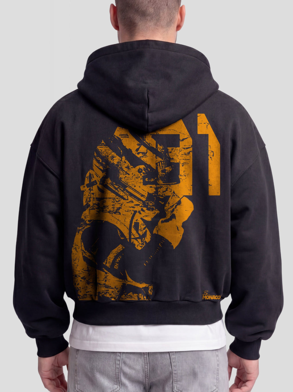 Model wearing the Racer No. 81 Heavyweight Full-Zip Hoodie in Faded Black with papaya-orange racing driver graphic — Monaco Social Club streetwear