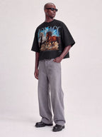 Full-length view of model in Monaco Run Wild black boxy tee with horse graphic and MONACO arch.