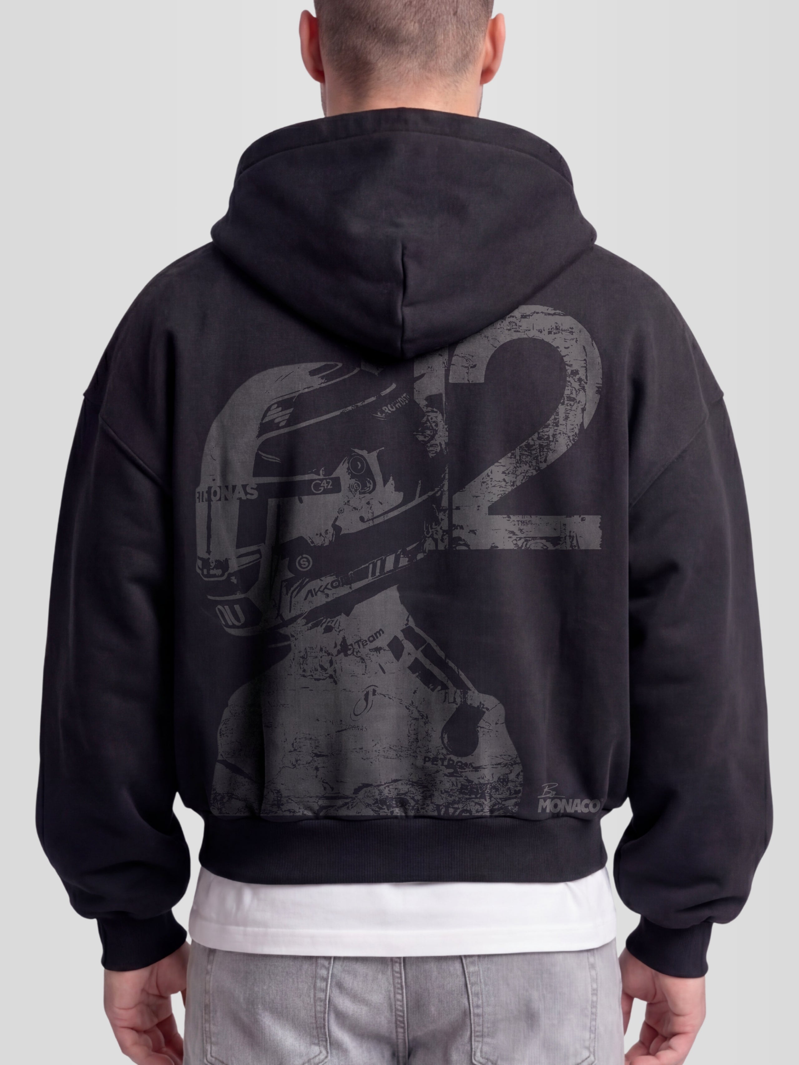 Model wearing the Racer No. 12 Heavyweight Full-Zip Hoodie in Faded Black with teal racing driver graphic — Monaco Social Club