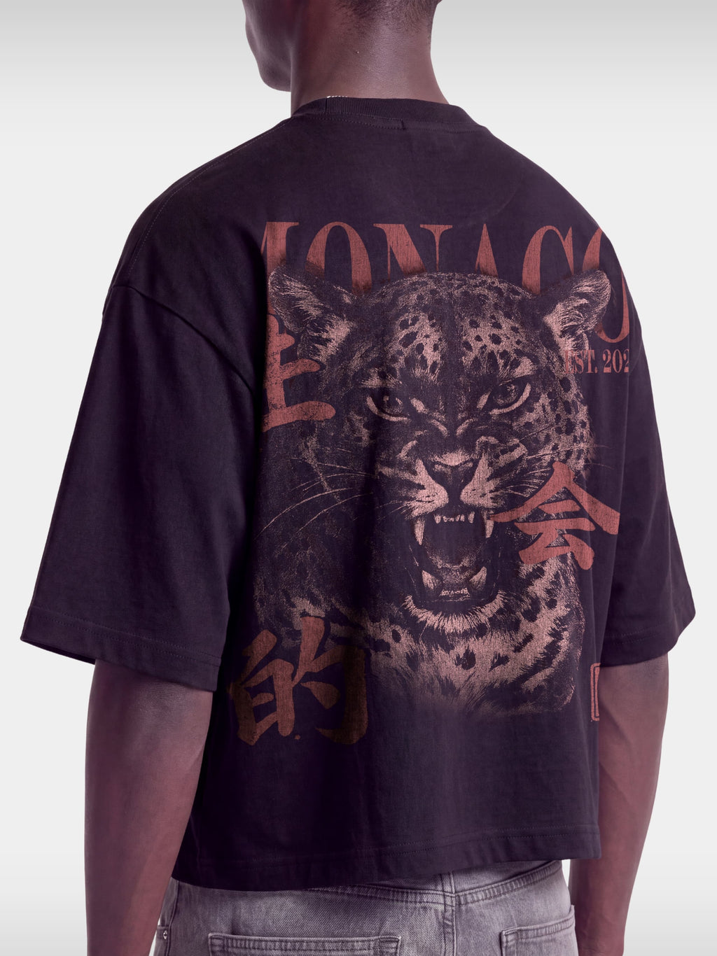 Cropped back view of Monaco Primal Instinct black boxy tee on model, washed leopard graphic.