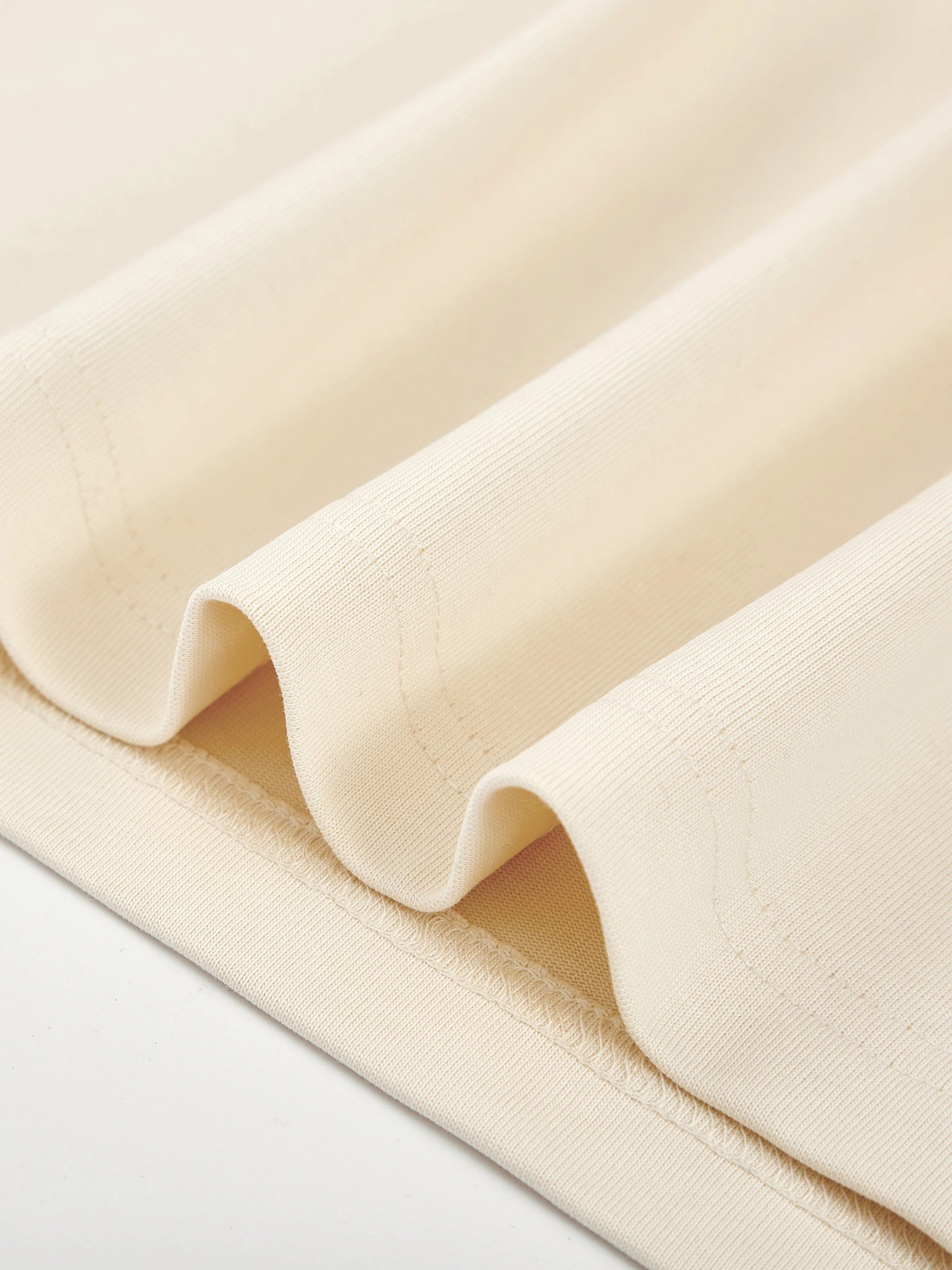 Close-up of Monaco ivory boxy tee showing 280 GSM cotton fabric and stitched hem.