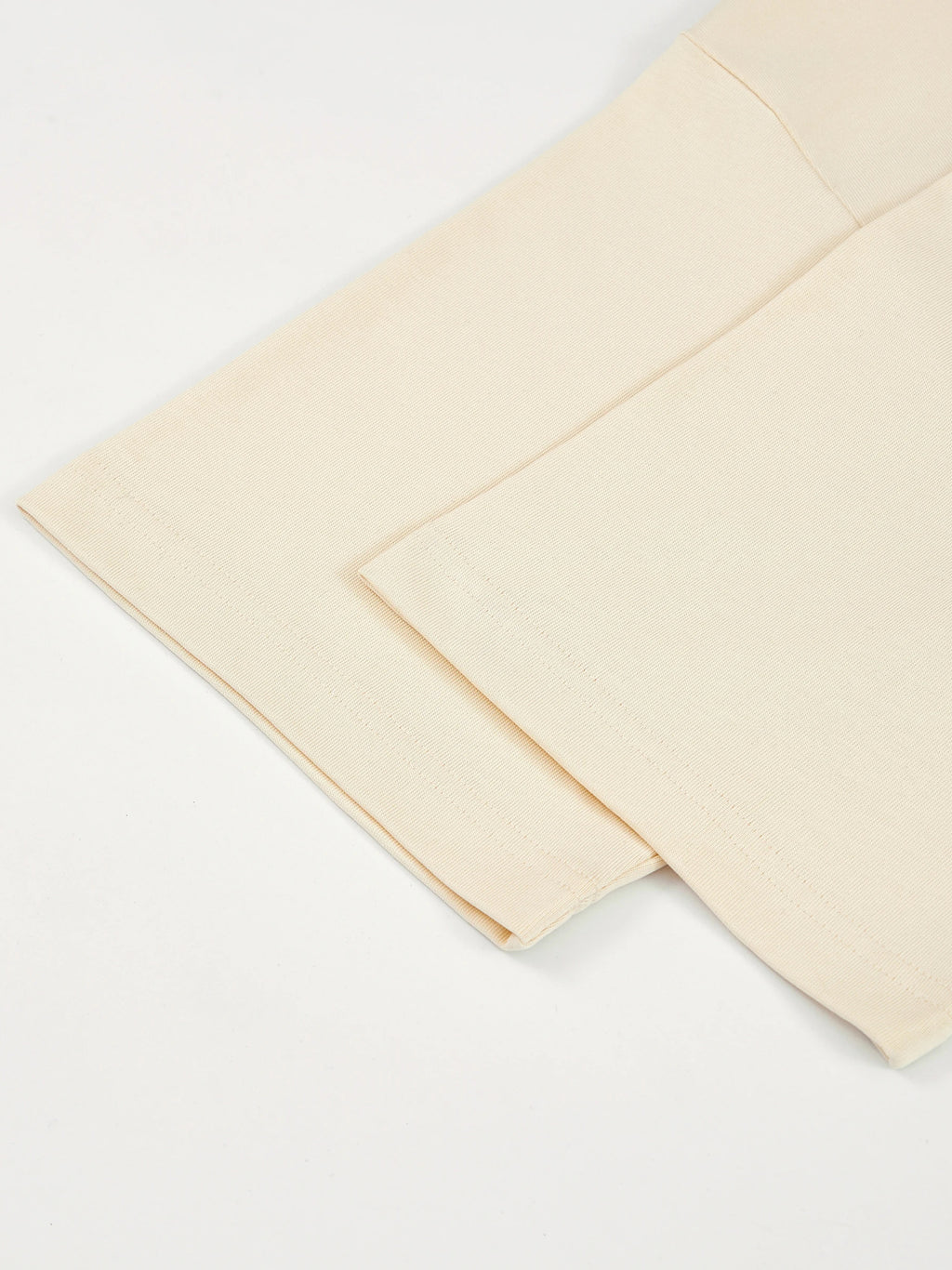 Monaco ivory boxy tee detail: folded sleeve, hem stitching and side seam.