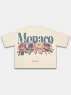 Ivory Bloom boxy tee by Monaco, back view with blue-green wordmark above four faded roses.