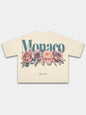 Ivory Bloom boxy tee by Monaco, back view with blue-green wordmark above four faded roses.
