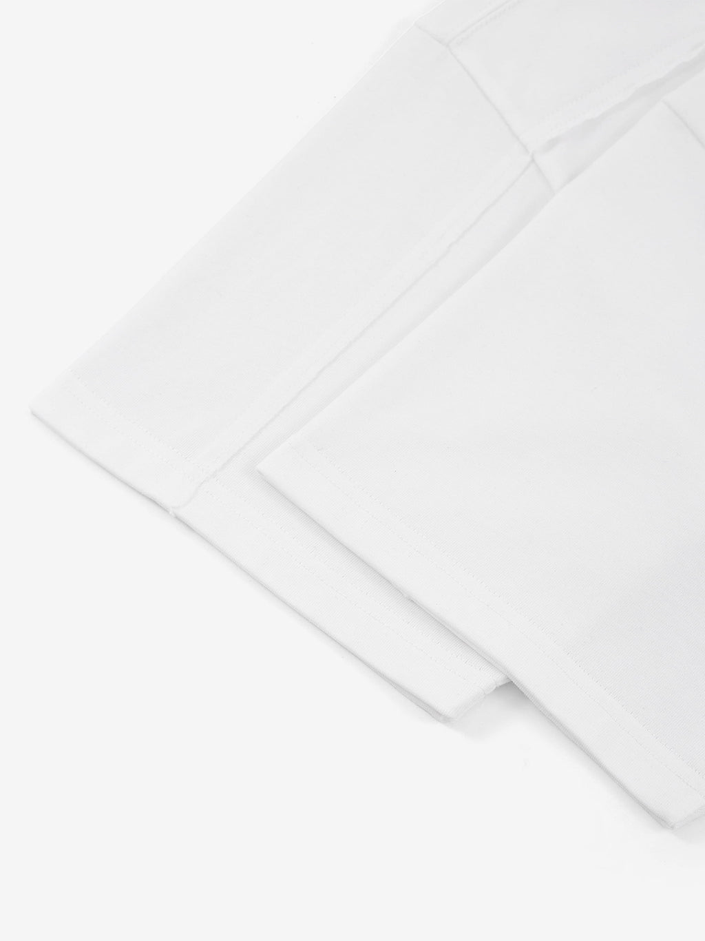 White Monaco paneled shirt detail showing sleeve hem and structured panel seam.